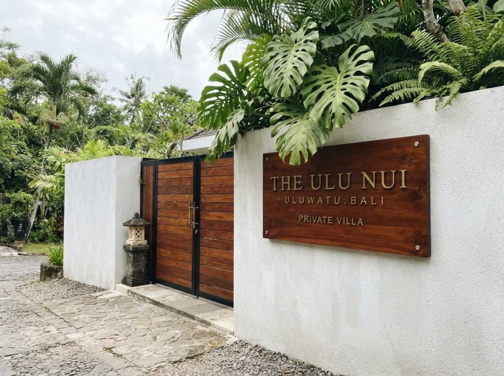 A luxury holiday estate entrance utilizing a custom villa sign bali crafted from seasoned teak wood and solid brass.