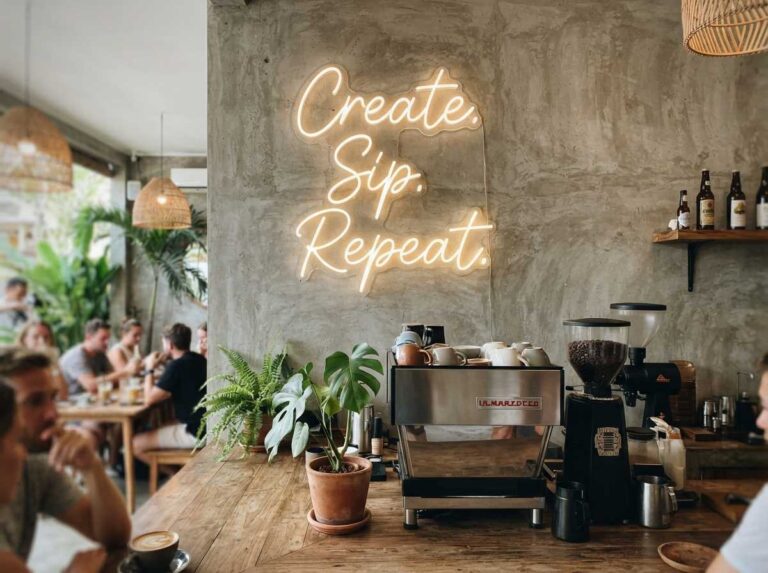 Sudut estetik kedai kopi yang menampilkan inspirasi neon sign untuk interior cafe berwarna putih hangat pada dinding semen.