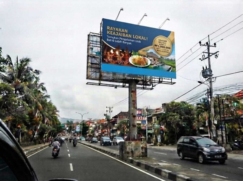Pemasangan reklame outdoor bali berbentuk billboard vertikal yang kokoh di pinggir jalan raya.