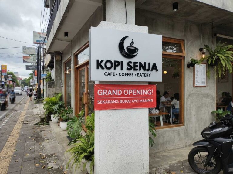Eksterior toko pariwisata baru yang memasang perangkat signage untuk bisnis baru buka berupa papan nama akrilik modern.
